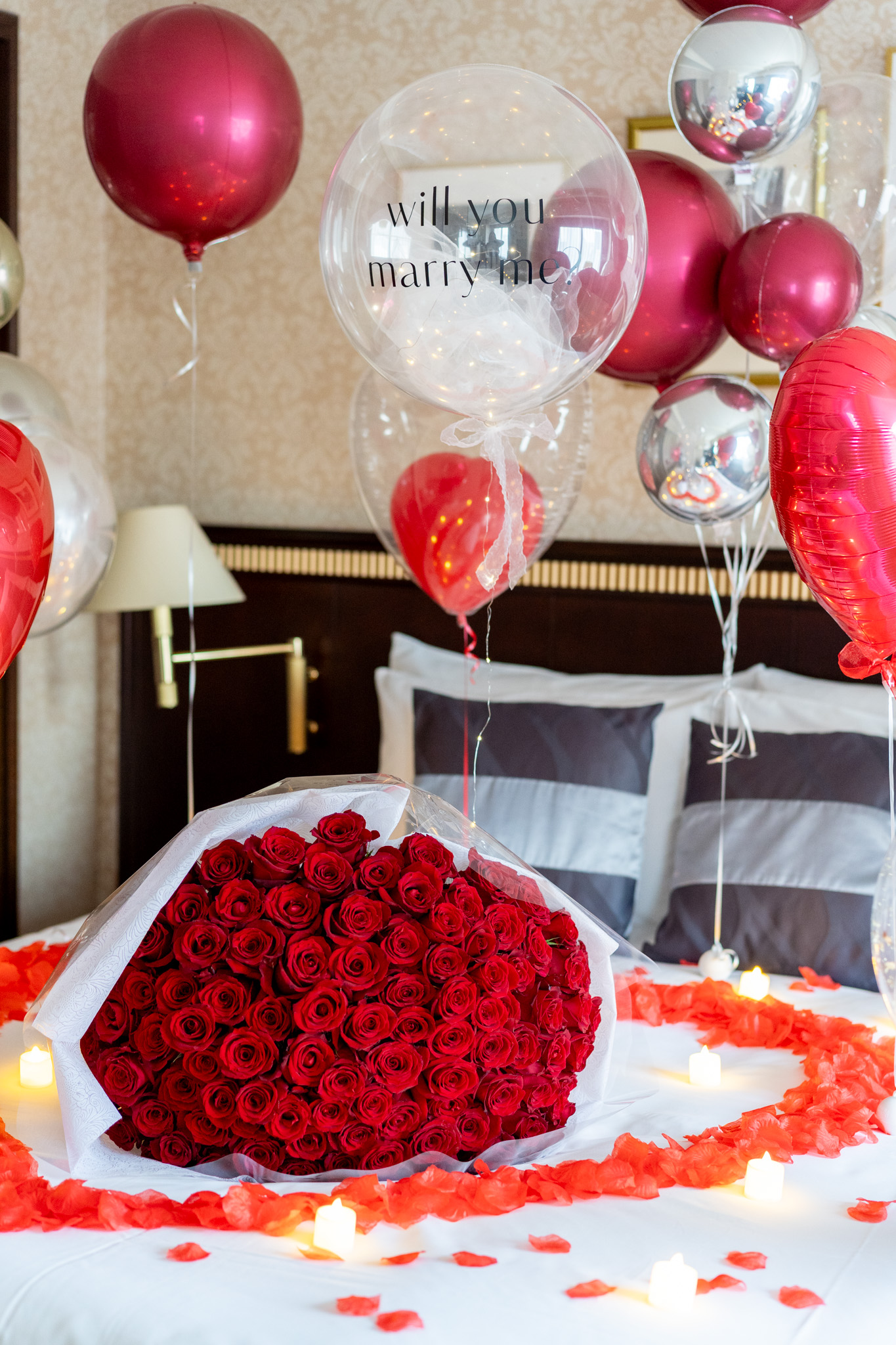 ベッドの上の108本の赤い薔薇の花束と、「will you marry me」の文字入りバルーン