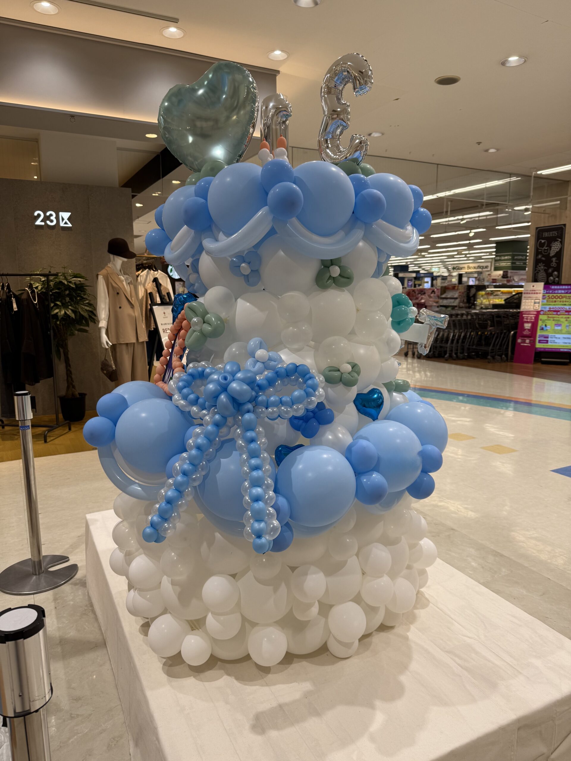 ショッピングモールの館内に置いた、ブルーのリボンを結んだケーキ形のバルーン