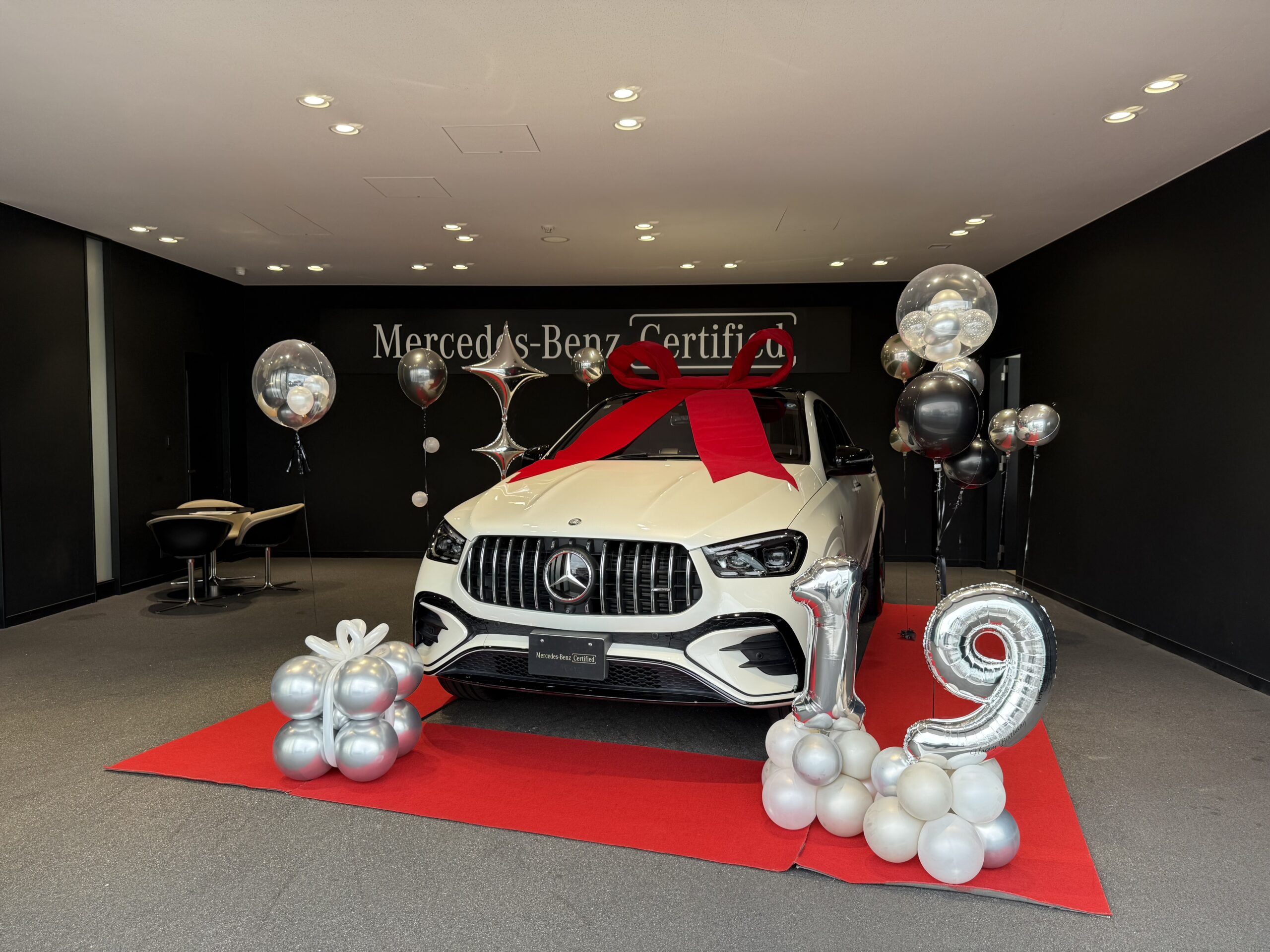 ショールームの白い車を、シルバーとブラックのバルーンで囲んだ納車式の装飾